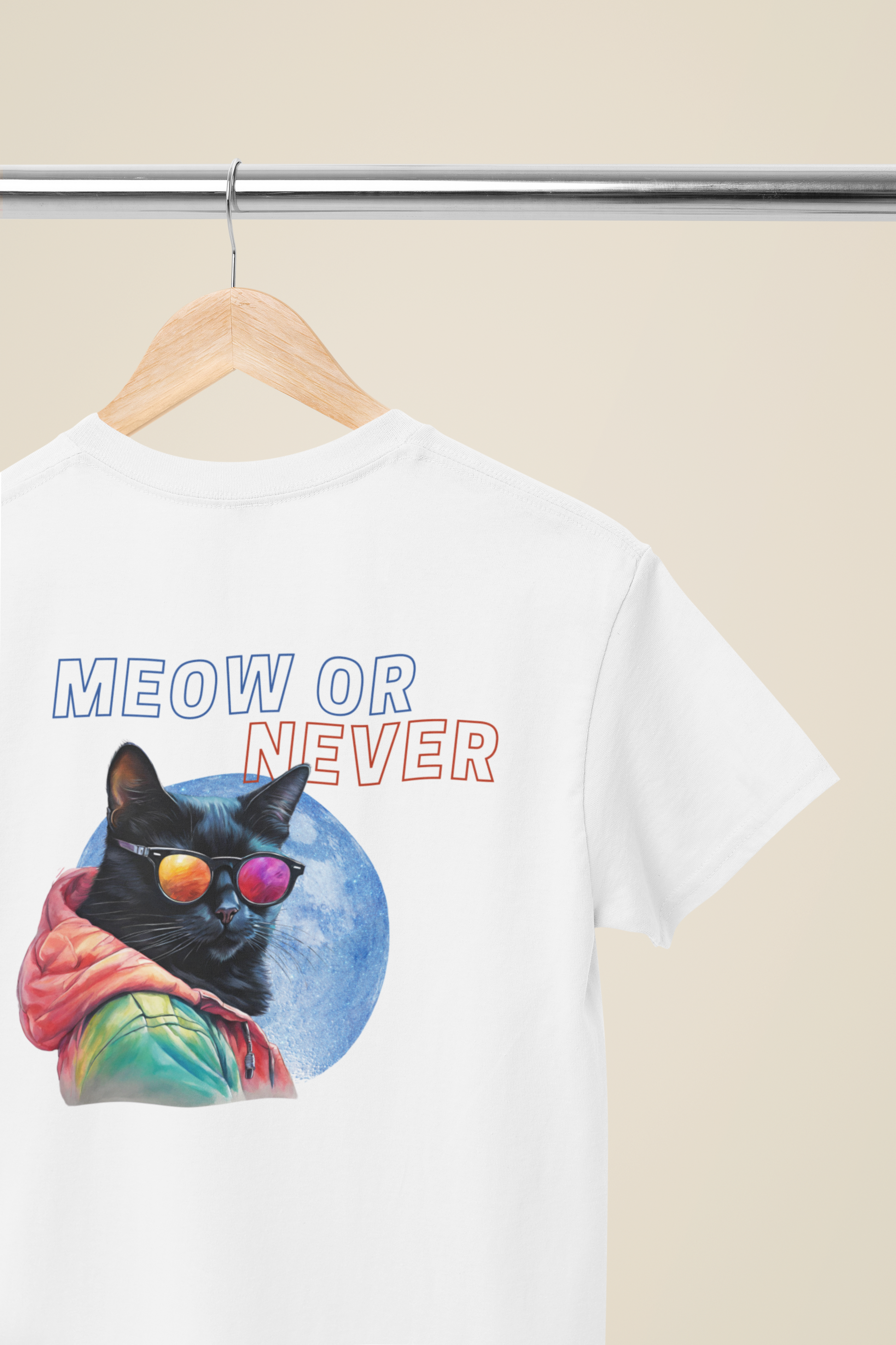 Back view of a white T-shirt with a cat in sunglasses and the text 'Meow or Never' displayed on a wooden hanger.