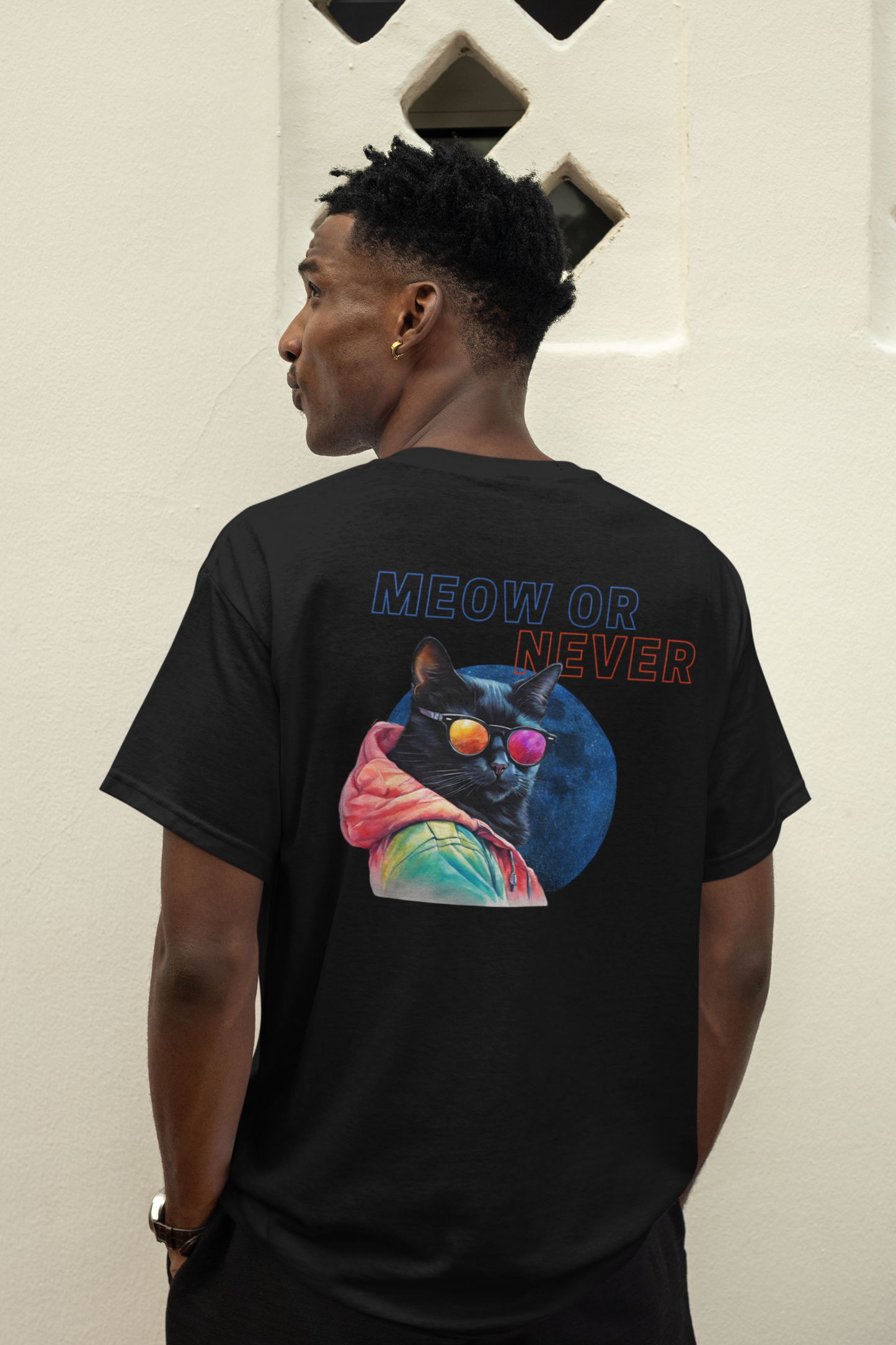 Side view of a man wearing a black T-shirt with a colorful cat and the text 'Meow or Never' on the back.